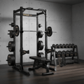 TITAN Elite black power rack with barbell, weights, adjustable bench, dumbbell rack, and bands against concrete wall.