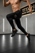 Black Titan Elite Training joggers with gold logo, featuring ribbed paneling and a slim, tapered athletic fit.
