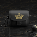 Matte black golf rangefinder bag with embroidered gold crown logo, snap closure, and black carabiner on marble surface.