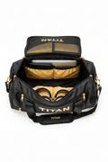 Open black TITAN Duffel Pro gym bag with gold interior, laptop compartment, mesh pockets, and gold logo accents.