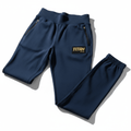 Navy tapered joggers featuring zip pockets, an elastic waistband and cuffs, and a gold TITAN logo patch.
