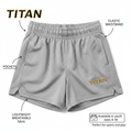 Gray girls' athletic shorts with elastic waistband, side pockets, side slits, and gold embroidered TITAN logo.