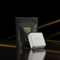 White square chalk block with gold TITAN logo, placed before a black pouch with gold text on a reflective surface.