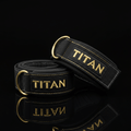 Black padded cotton lifting straps with gold "TITAN" embroidery, gold D-rings, and gold stitching on black background.