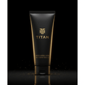 Matte black TITAN shaving cream tube with gold logo and text, set against a dark background with gold dust particles.