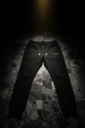 Black slim-fit fleece joggers with gold drawstring aglets and TITAN logo on a textured grey marble floor.