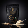 Black TITAN Quinoa Protein pouch with gold logo, text, and scoop of powder on a reflective surface.