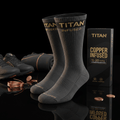 Two dark grey Titan copper-infused compression socks next to branded black packaging, copper wire, and athletic shoes.