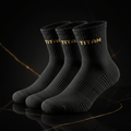 Three black TITAN performance running socks with gold-stitched branding on ribbed cuffs, set on a marble surface.