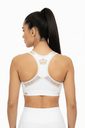 TITAN white racerback sports bra featuring gold crown logo and detailing on back, worn by model.