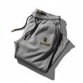 Gray heathered TITAN sweatpants with black drawstring, gold-tipped aglets, and a black and gold Spartan logo.