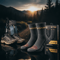 Two gray TITAN anti-blister trail running socks featuring gold branding and red toe accents, shown with product box.