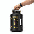 Matte black 128oz TITAN gallon jug with gold branding and hydration time markers, held by a hand on a white background.
