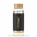 TITAN 22oz glass water bottle with bamboo lid, black silicone sleeve, gold logo, and gold base.
