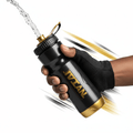 Black and gold TITAN sport squeeze bottle held in a gloved hand with water spraying from the nozzle.