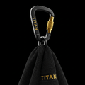 Black TITAN workout towel hanging from a matte black carabiner with gold branding and a textured gold locking nut.