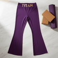Purple high-waist flare yoga pants with gold "TITAN" logo on waistband, laid flat on marble with yoga props.